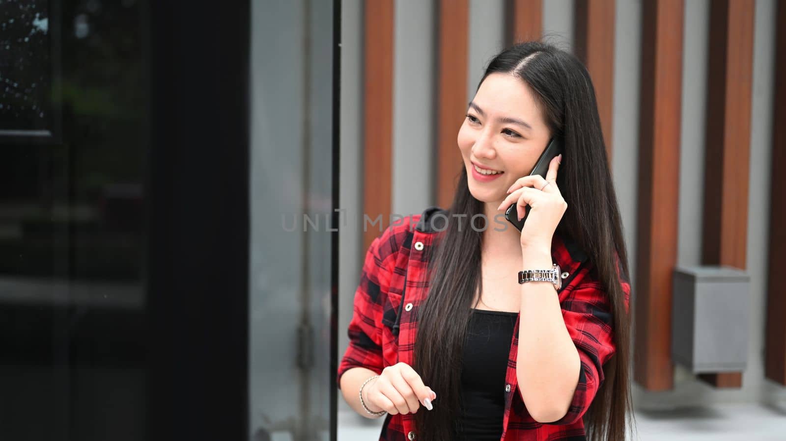 Young Asian woman standing at outdoor and talking on mobile phone.