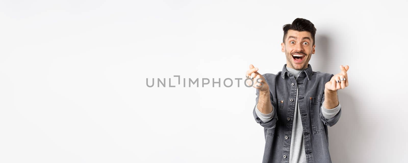 Excited romantic man showing hand hearts and smiling at camera, express love and affection, standing on white background by Benzoix