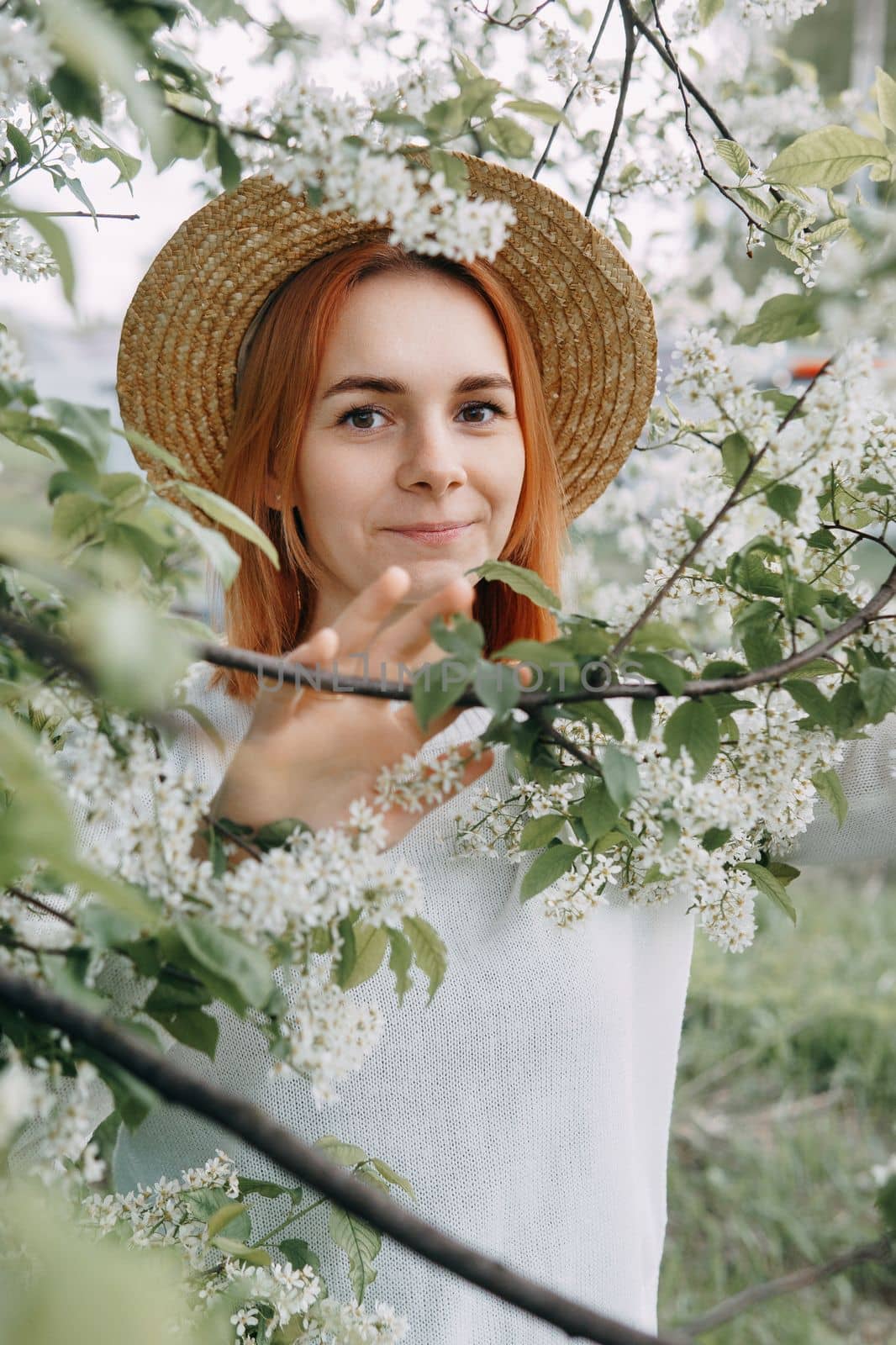 Portrait of a woman in a straw hat in a cherry blossom. Free outdoor recreation, spring blooming garden