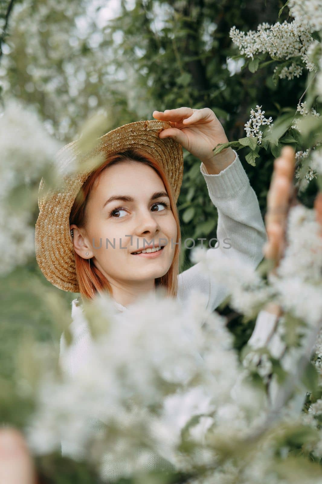 Portrait of a woman in a straw hat in a cherry blossom. Free outdoor recreation, spring blooming garden