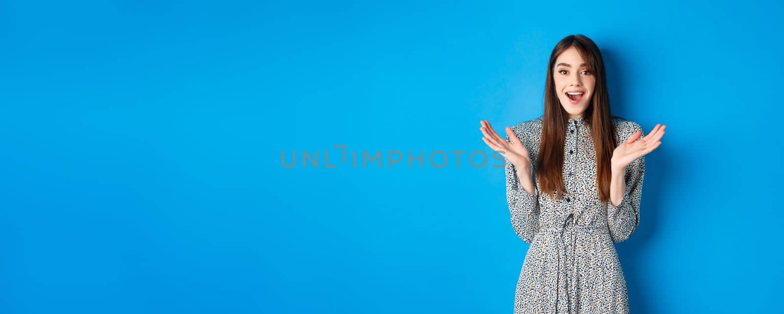 Excited beautiful woman clap hands and congratulate you, praising nice work, applause at camera and smiling, standing on blue background by Benzoix