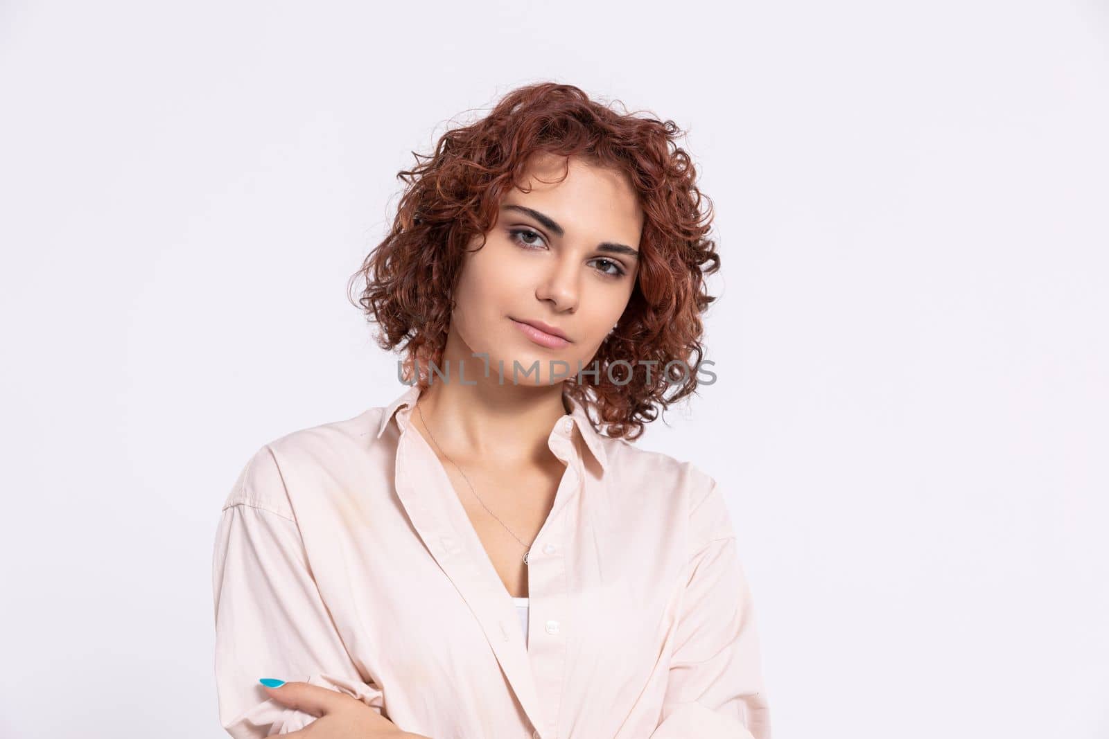 A gentle smile on her face. A European woman with chestnut-colored hair. A girl with fair skin and curly short hair looks straight ahead.