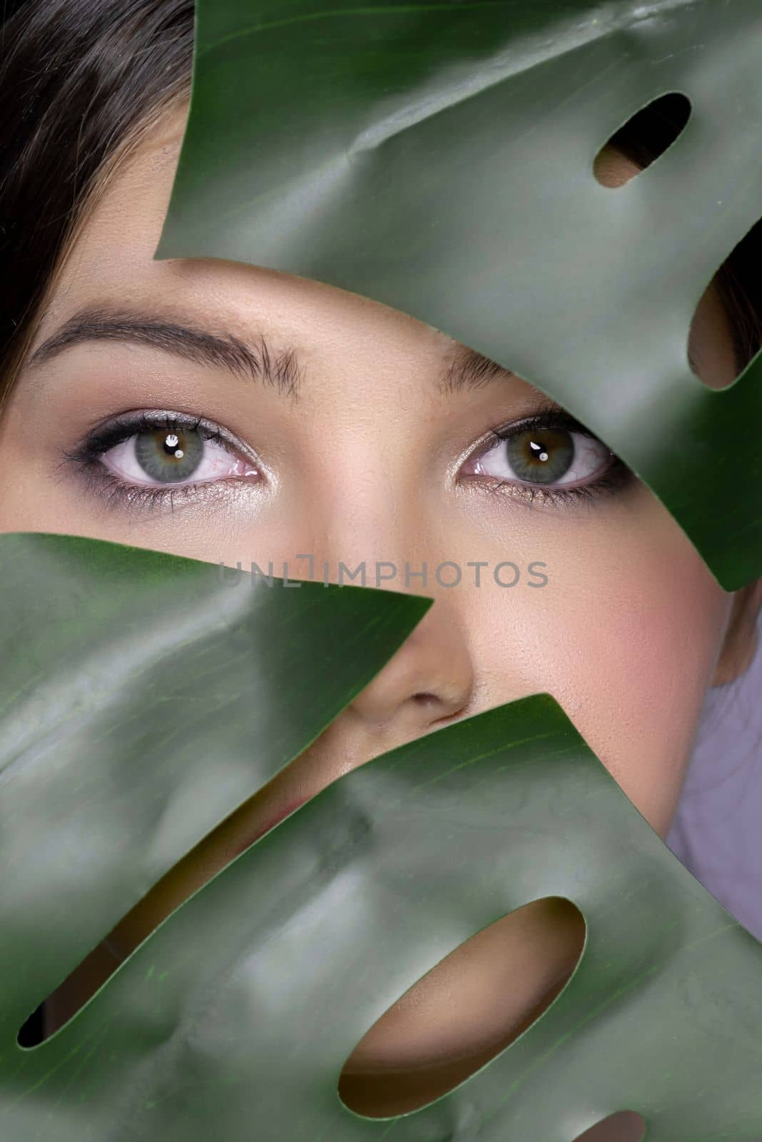 Closeup portrait face of charming girl covered with green leaf in beauty concept by biancoblue