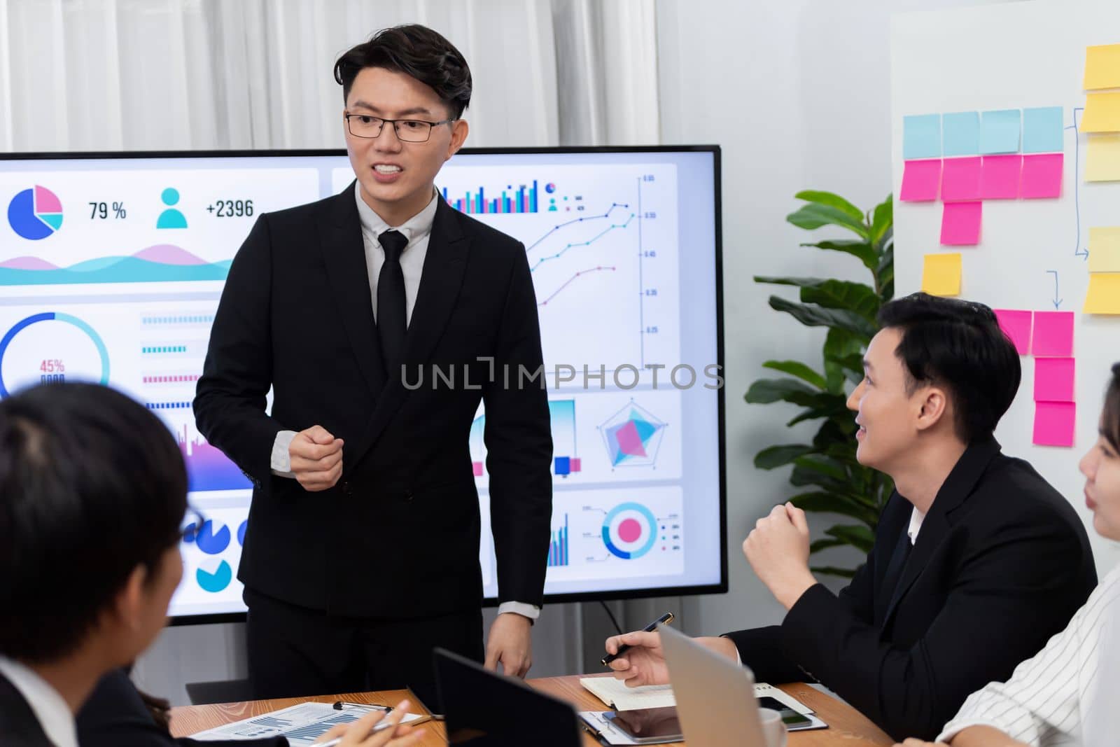 Confidence and asian businessman give presentation on financial analyzed by business intelligence in dashboard report to other people in board room meeting to promote harmony in workplace.