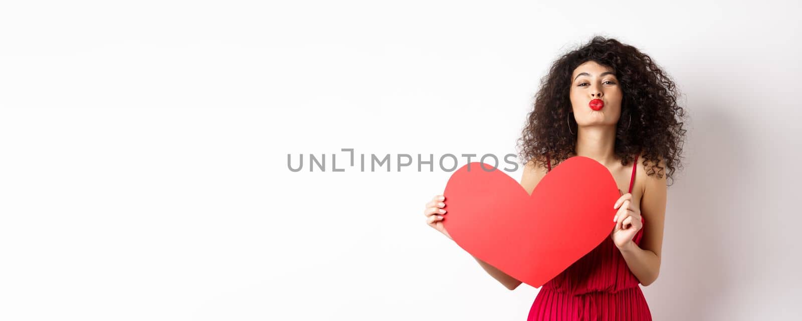 Romantic woman in dress showing big red heart, pucker lips for kiss and express love, express sympathy, white background by Benzoix