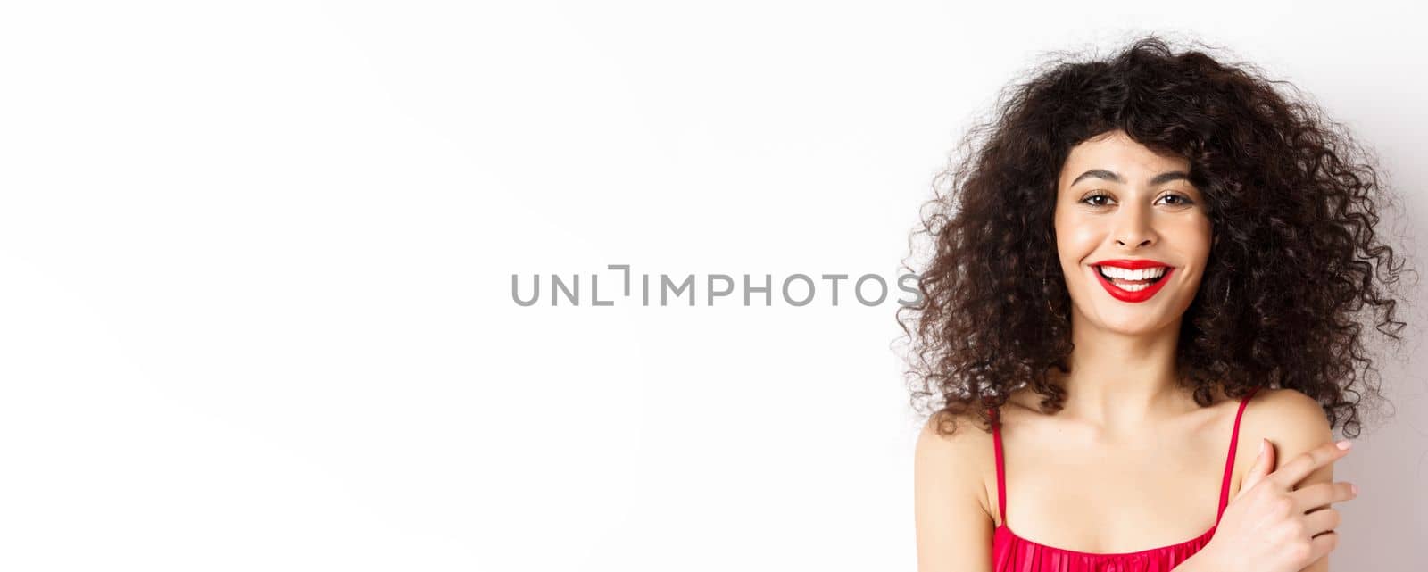 Close-up portrait of beautiful lady with curly hair and red lips, smiling and laughing happy, standing on white background.