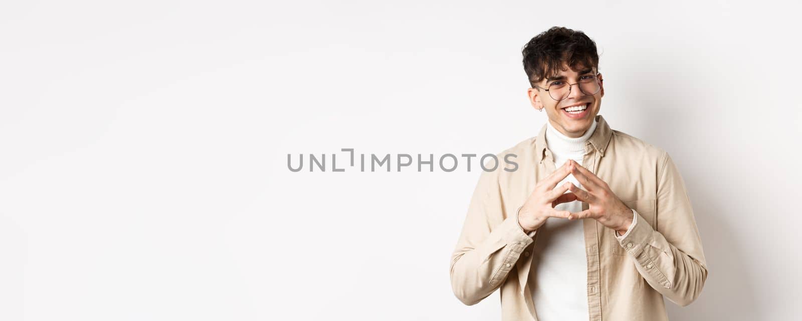 Portrait of hipster guy in glasses with white smile, steeple fingers as having plan, scheming something interesting, standing cunning on white background.