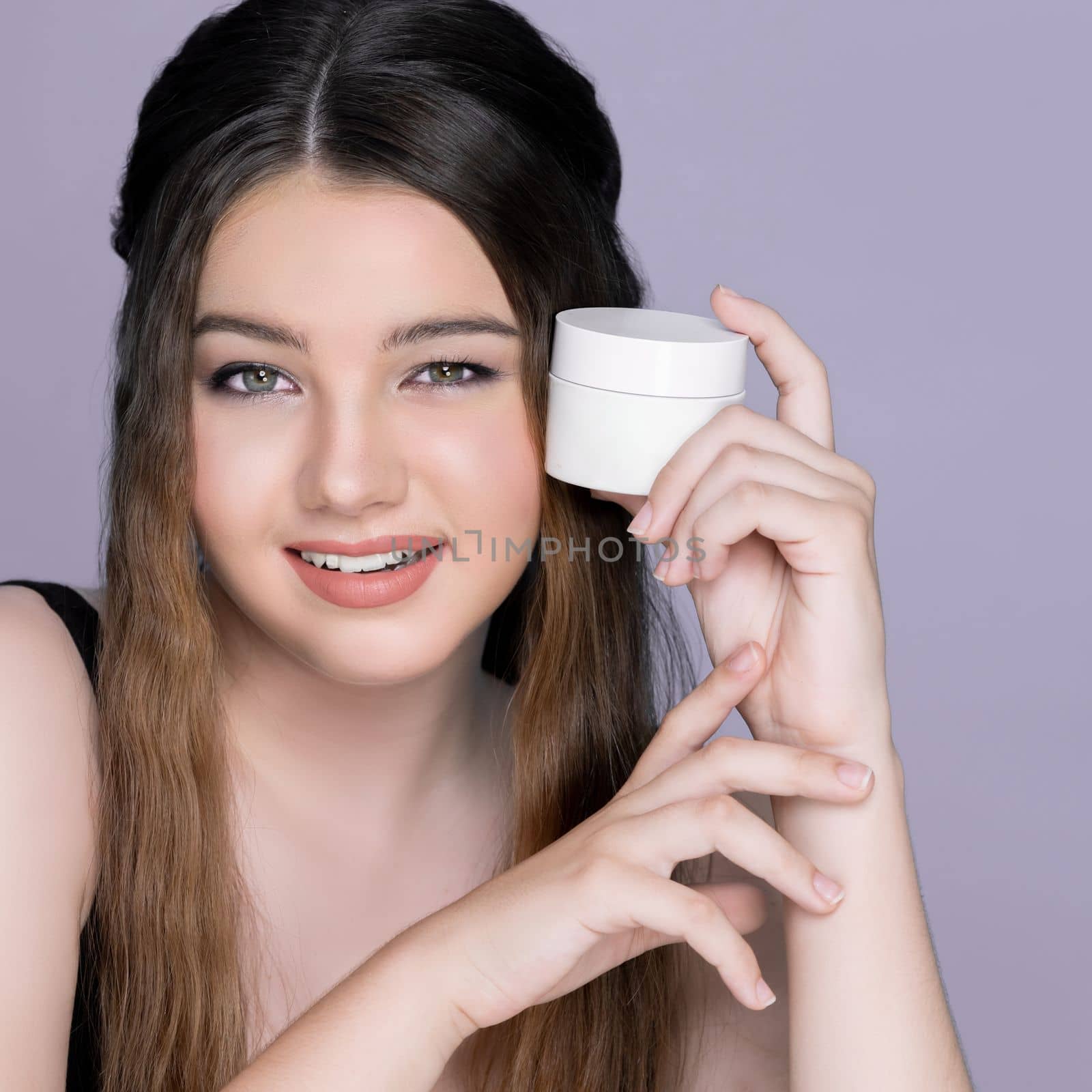 Young charming girl hold mockup moisturizer skincare cream jar or container for copyspace advertising. Photo of beautiful and attractive girl with perfect makeup for beauty concept.