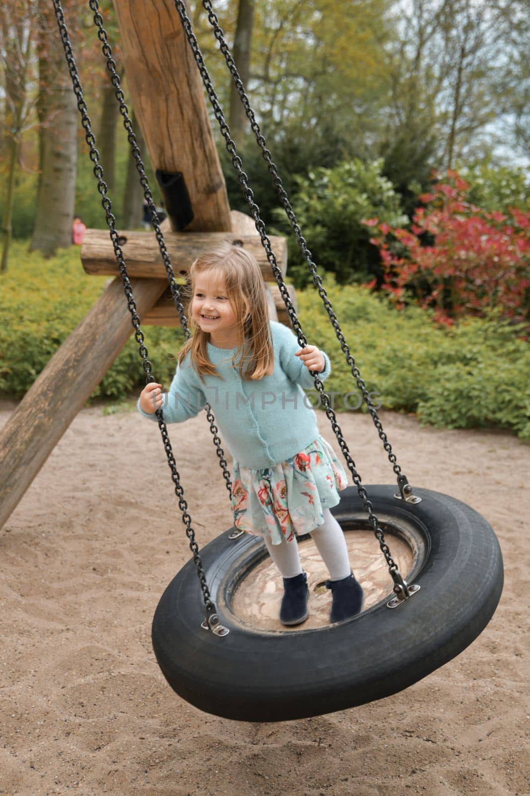 Girl of 4 years old riding on a swing in a park