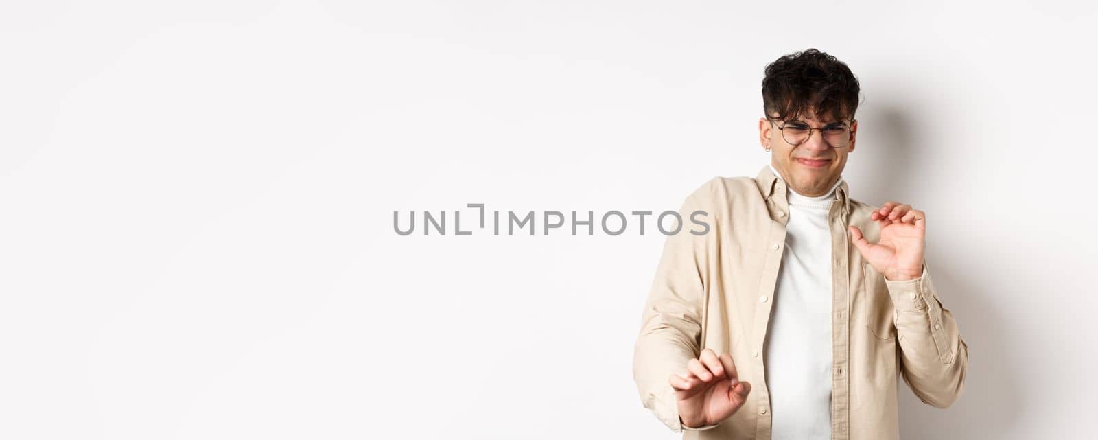 Disgusted guy grimacing and jumping away from something nasty, stare with aversion and dislike, rejecting bad offer, standing on white background by Benzoix