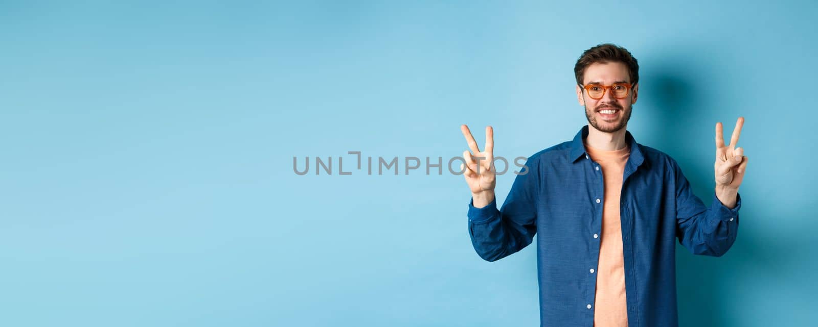 Cheerful guy posing with peace sign in new glasses, concept of eyewear shop promotion by Benzoix