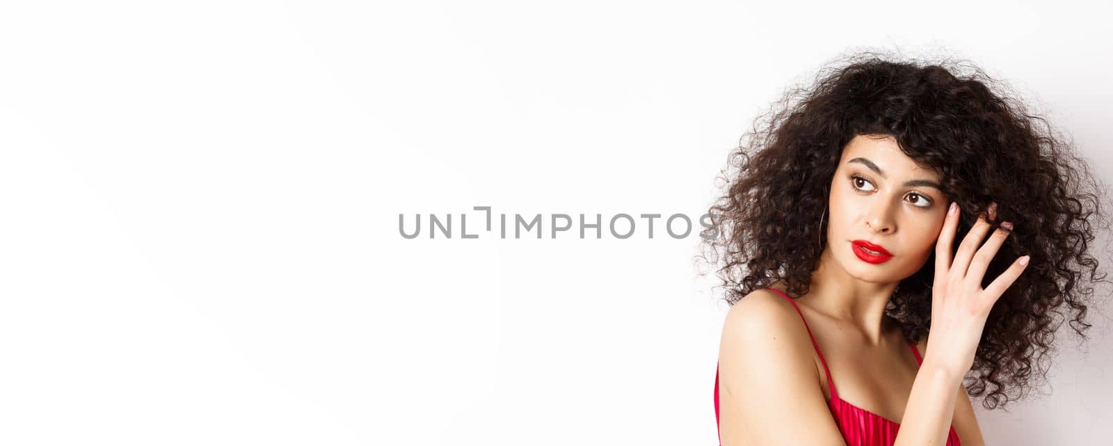Close-up of tender romantic woman, gently touching face and looking sensual aside, white background. Copy space