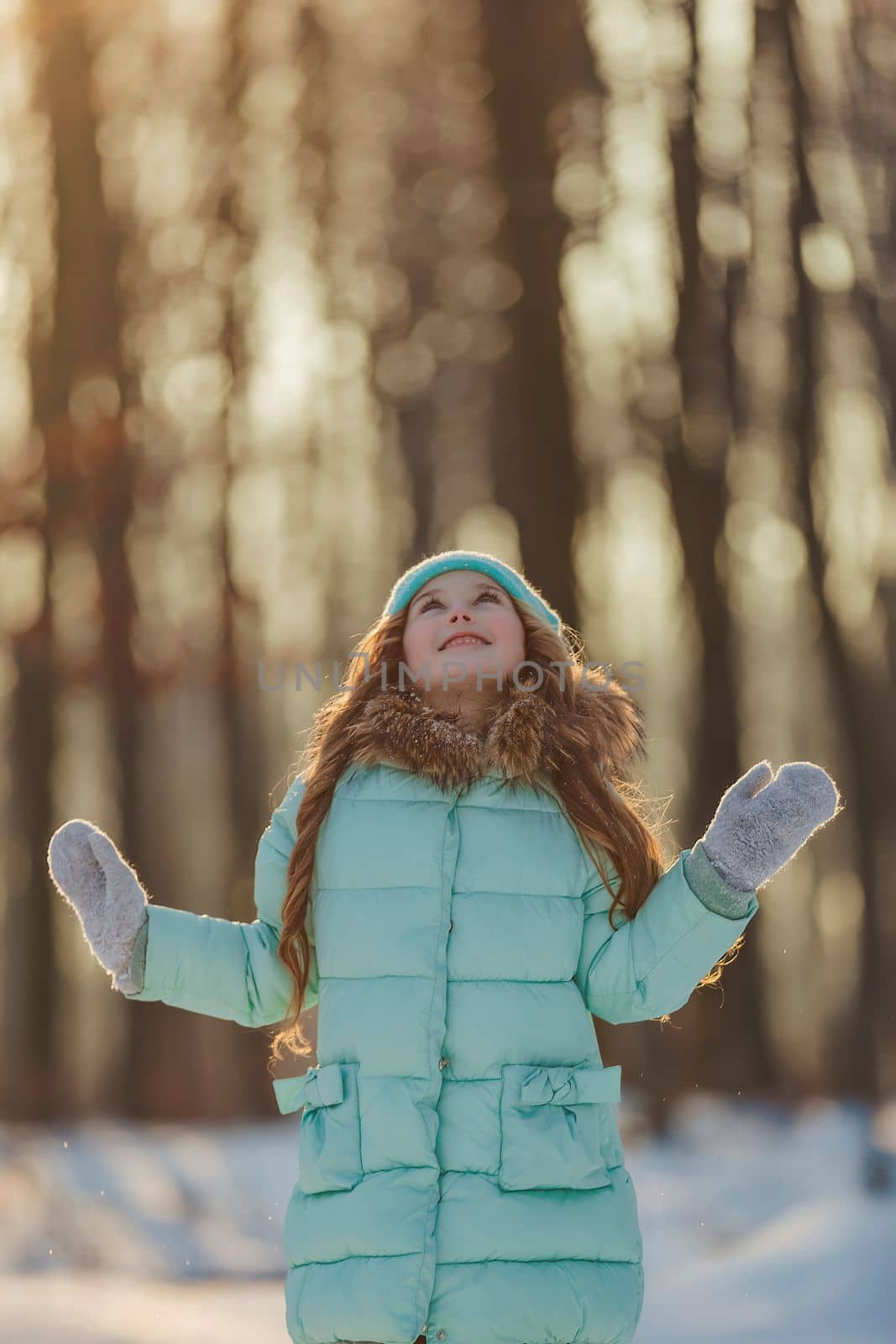 girl in a turquoise squat and a hat in a winter forest, shot vertically