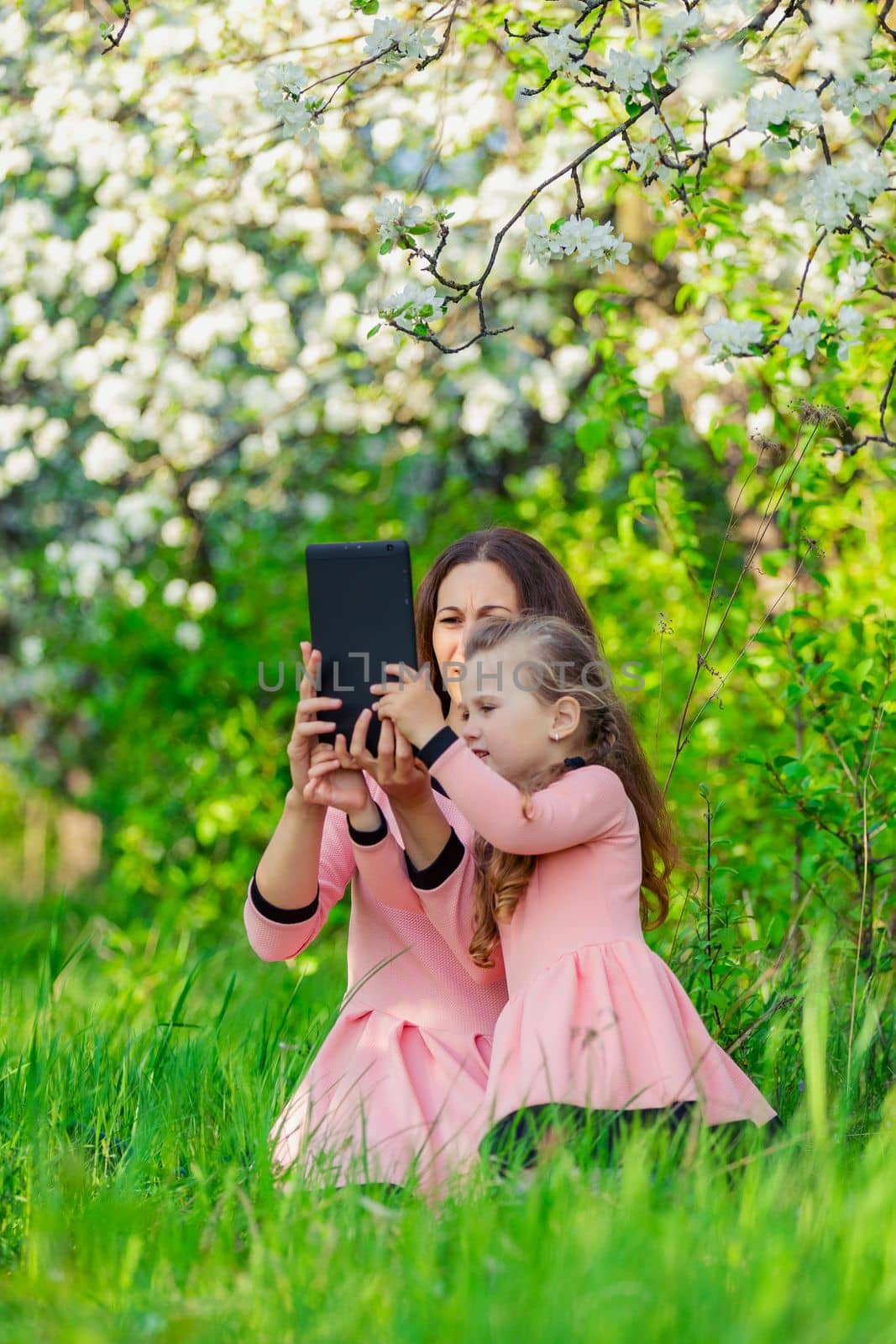 mother and daughter take pictures using a tablet in nature