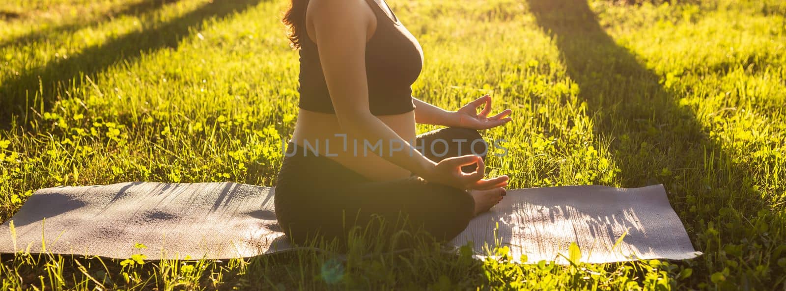 young pregnant woman meditating in nature, practice yoga. Care of health and pregnancy.