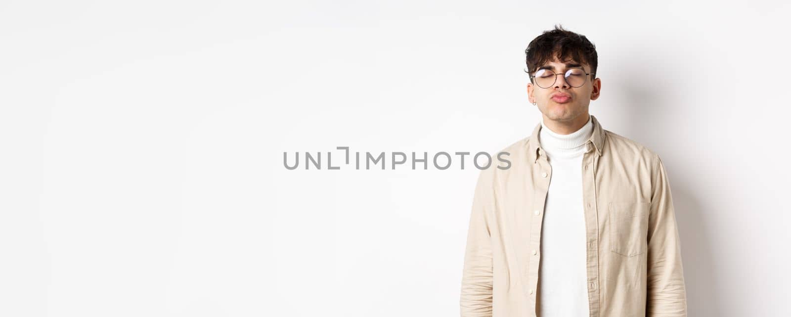 Cute boyfriend in glasses waiting for kiss, having romantic date on Valetines day, white background. Concept of relationship and romance by Benzoix