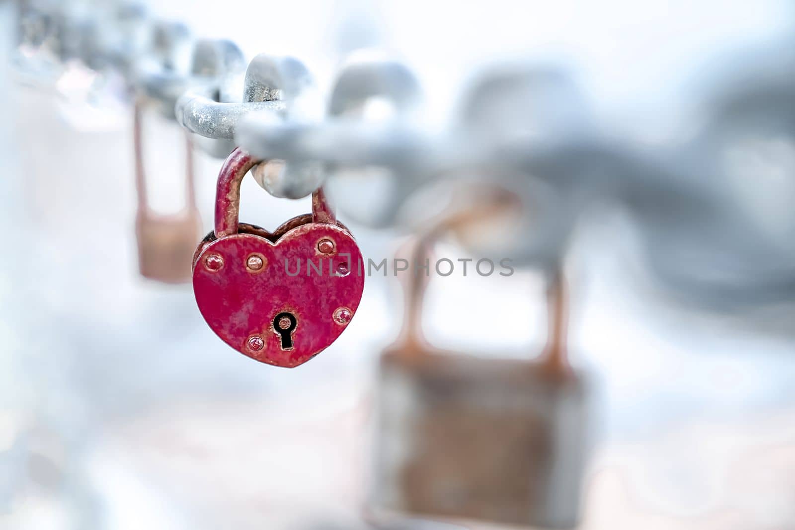 Red heart shaped lock hangs from chain, wedding custom, concept of love and health