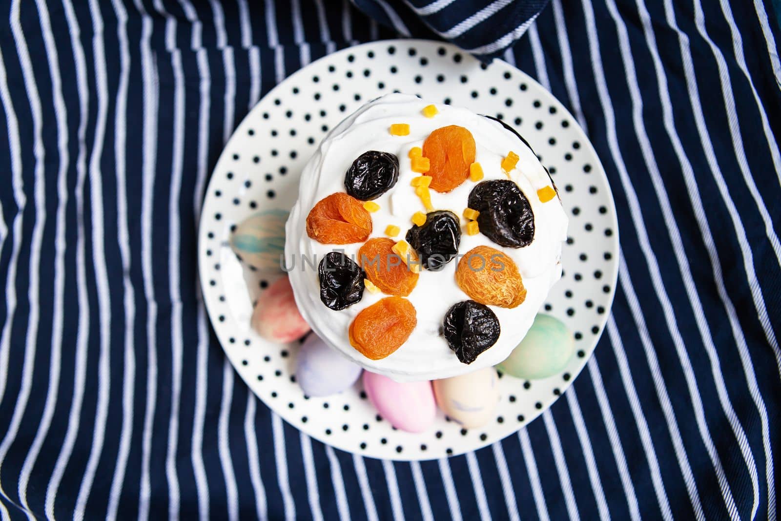 Easter eggs and Easter cake are on a plate, lying on a striped blue apron. Easter religious holiday concept