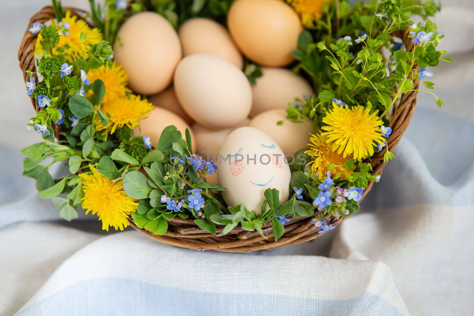 Beautiful spring bouquet in a wooden basket with Easter painted eggs, eggs with cute faces. Easter colorful card. View from above. by sfinks