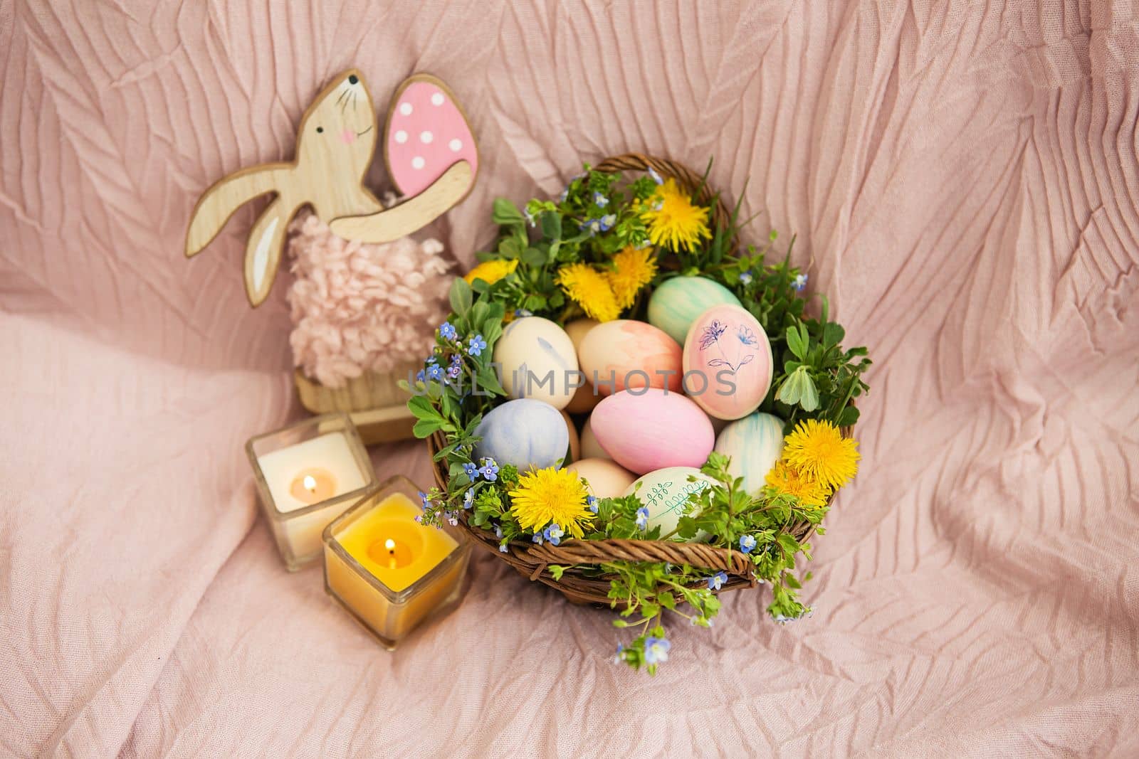 On a pastel bedspread is a basket of grass and various bright flowers, a rabbit. The basket contains Easter eggs painted with watercolors in beautiful pastel colors. by sfinks