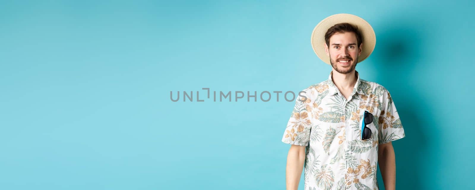 Happy and positive tourist in hawaiian shirt and straw hat, smiling at camera. Concept of tourism and summer holiday by Benzoix