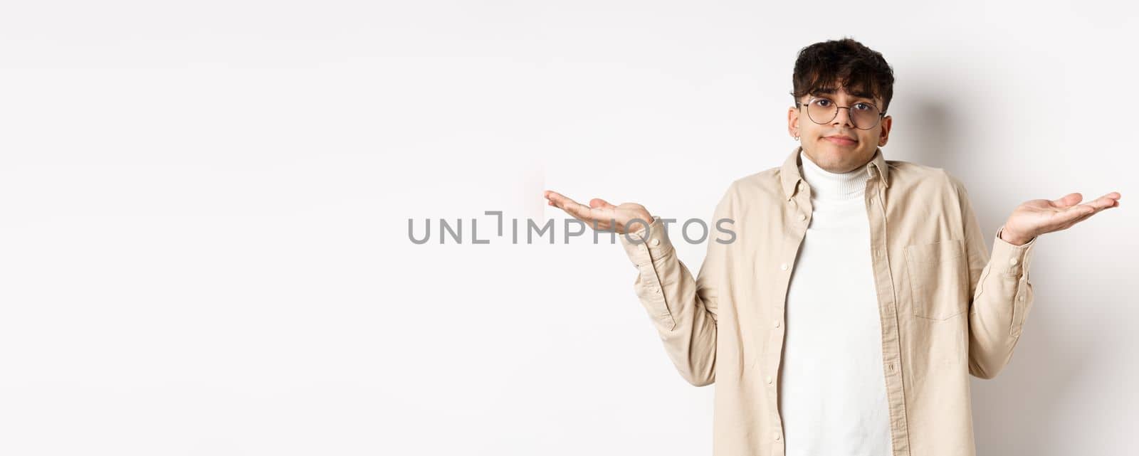 Portrait of handsome young man looking confused, know nothing, shrugging shoulders and spread hands sideways clueless, standing on white background by Benzoix