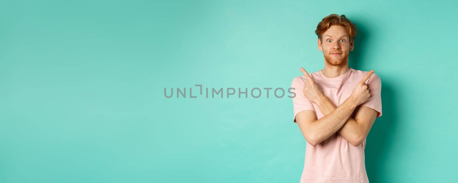 Attractive indecisive man in t-shirt cross hands and pointing sideways, showing two choices, need help with decision, standing over turquoise background by Benzoix