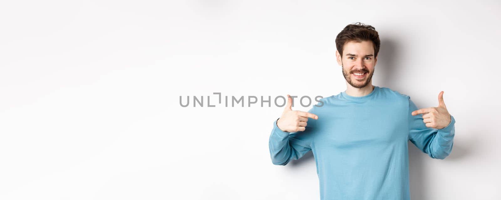 Handsome bearded man pointing fingers at center, self-promoting and looking confident, standing over white background, smiling at camera by Benzoix