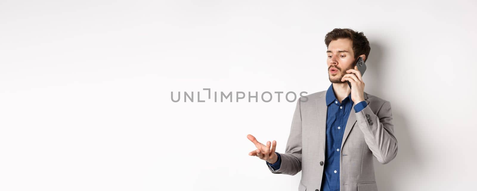 Handsome businessman having business call on phone, gesturing while talking on mobile, having conversation, white background.