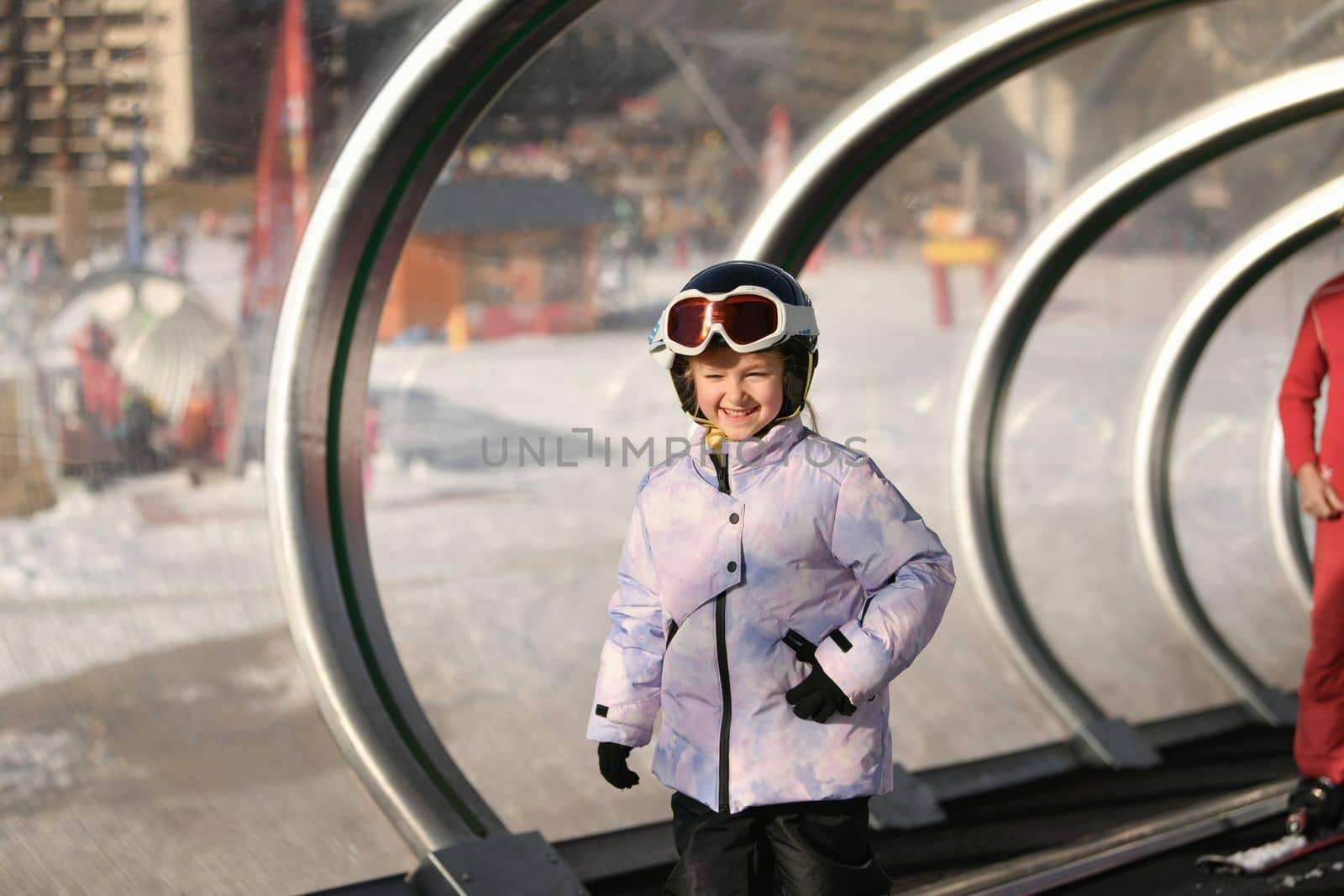 A girl on skis stands on a carpet ski lift in a tunel