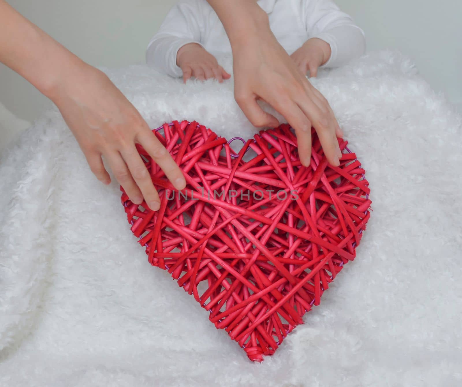 Red heart in the hands of mother with a child