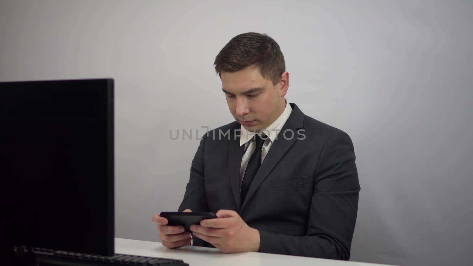 A young programmer plays a game on the phone. Businessman plays at work in the office plays smartphone. 4k