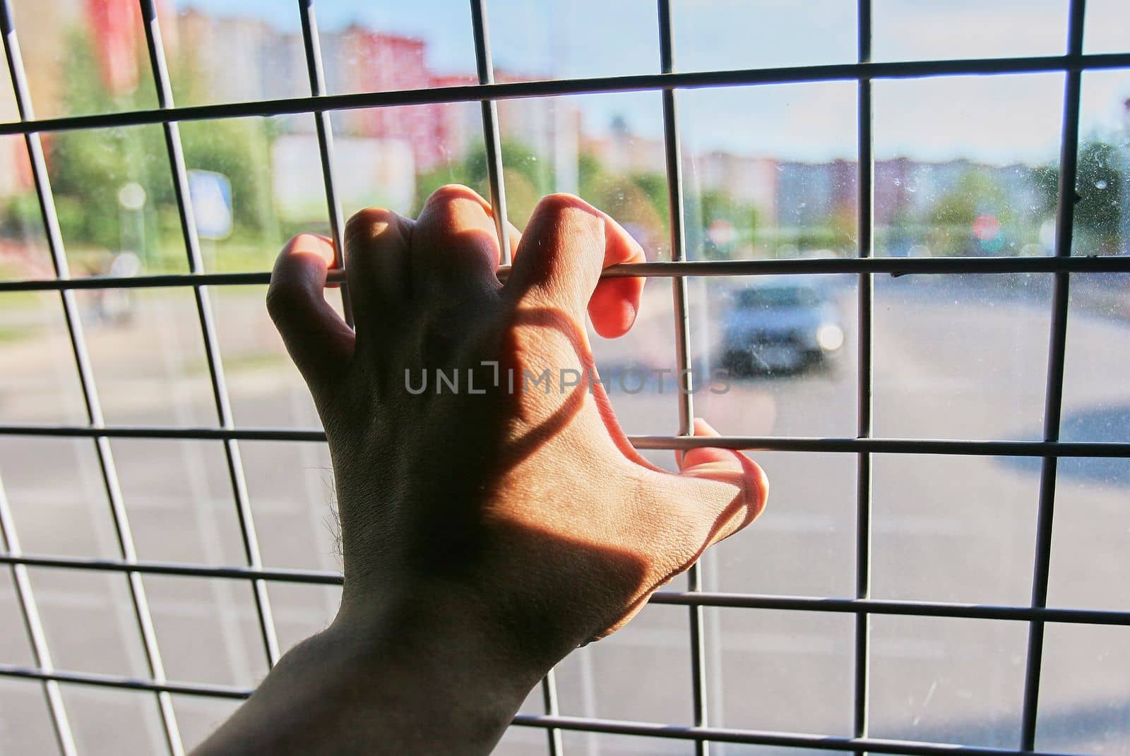 Man in prison hand holding a steel cage prison bars. criminal criminal is locked in prison. The hand of a detained man in a police car.