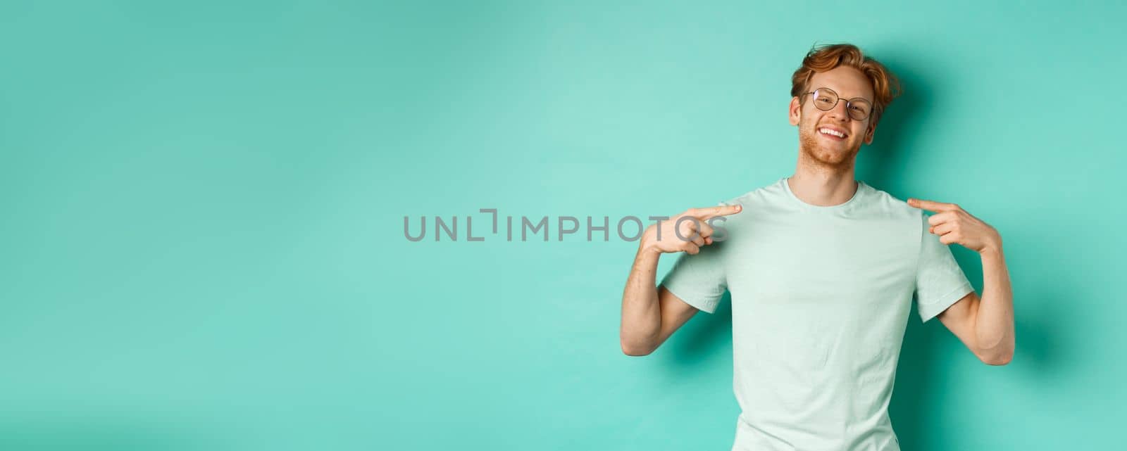Confident redhead man in glasses and t-shirt, smiling with smug face and pointing at himself, bragging while standing over turquoise background by Benzoix