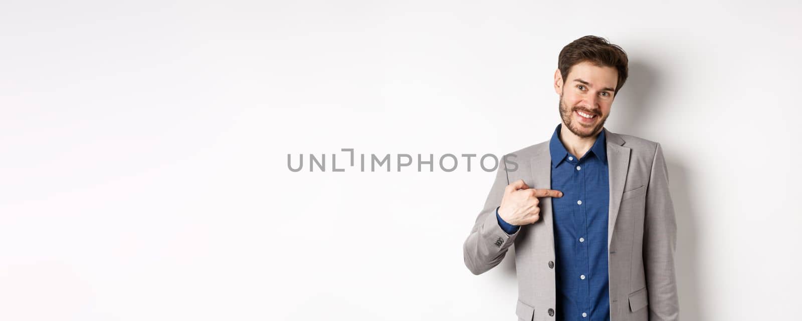 Modest smiling man in suit pointing at himself with cute face, self-promoting, standing on white background by Benzoix