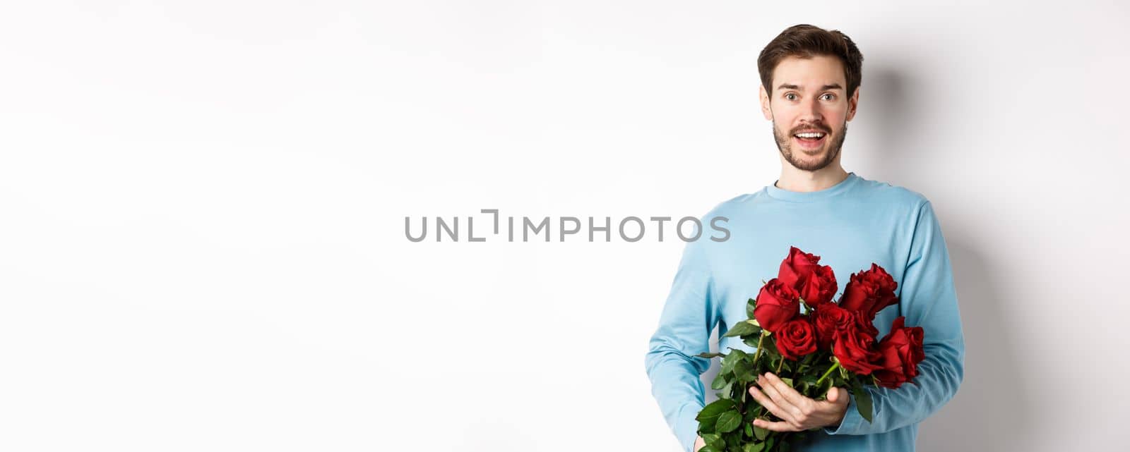 Romantic boyfriend bring beautiful bouquet of red roses on valentines day, having date with girlfriend, saying I love you, standing passionate on white background by Benzoix