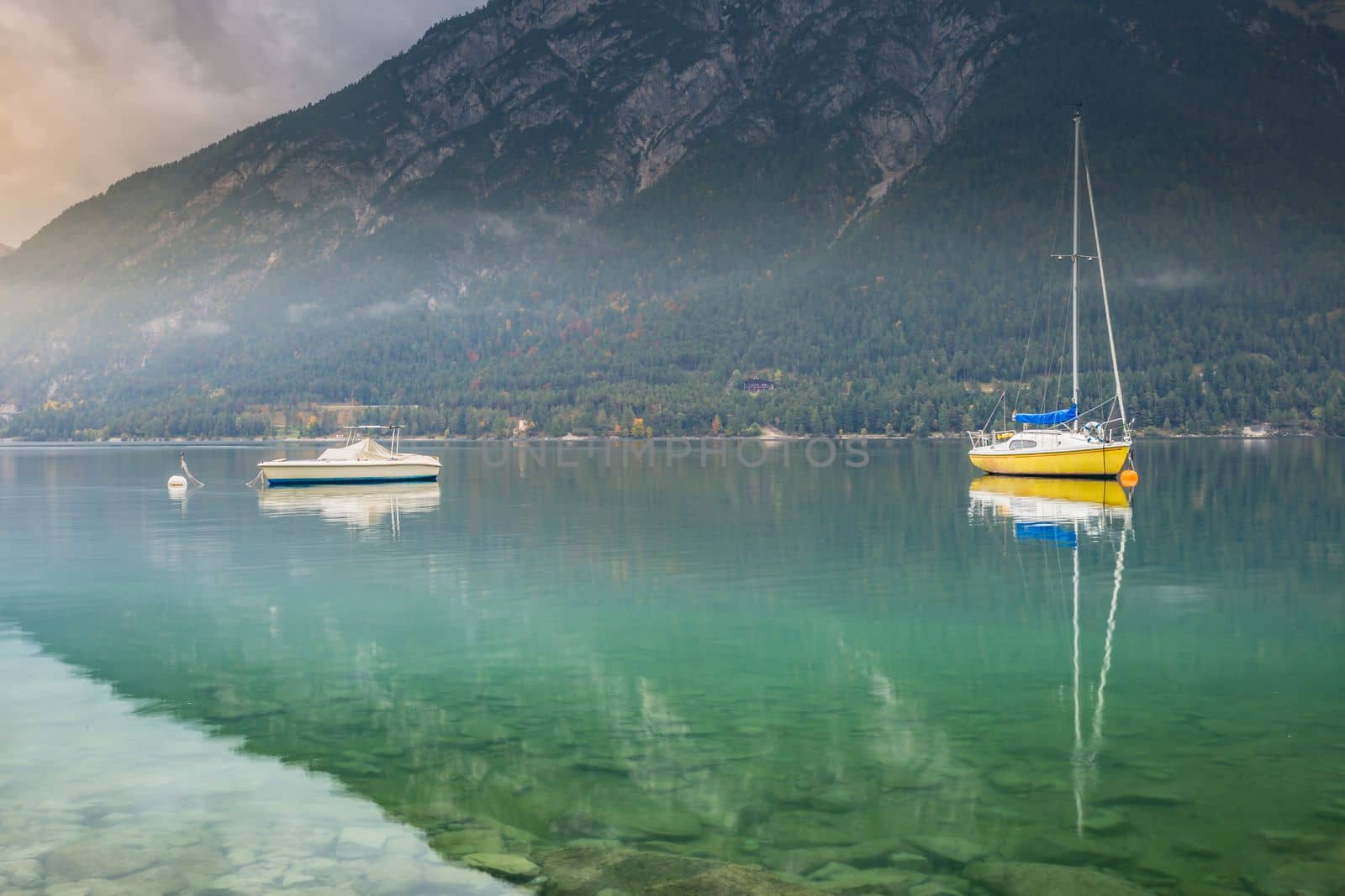 Sailboats on Achensee lake near Innsbruck at peaceful misty dawn, Tyrol alps, Austria