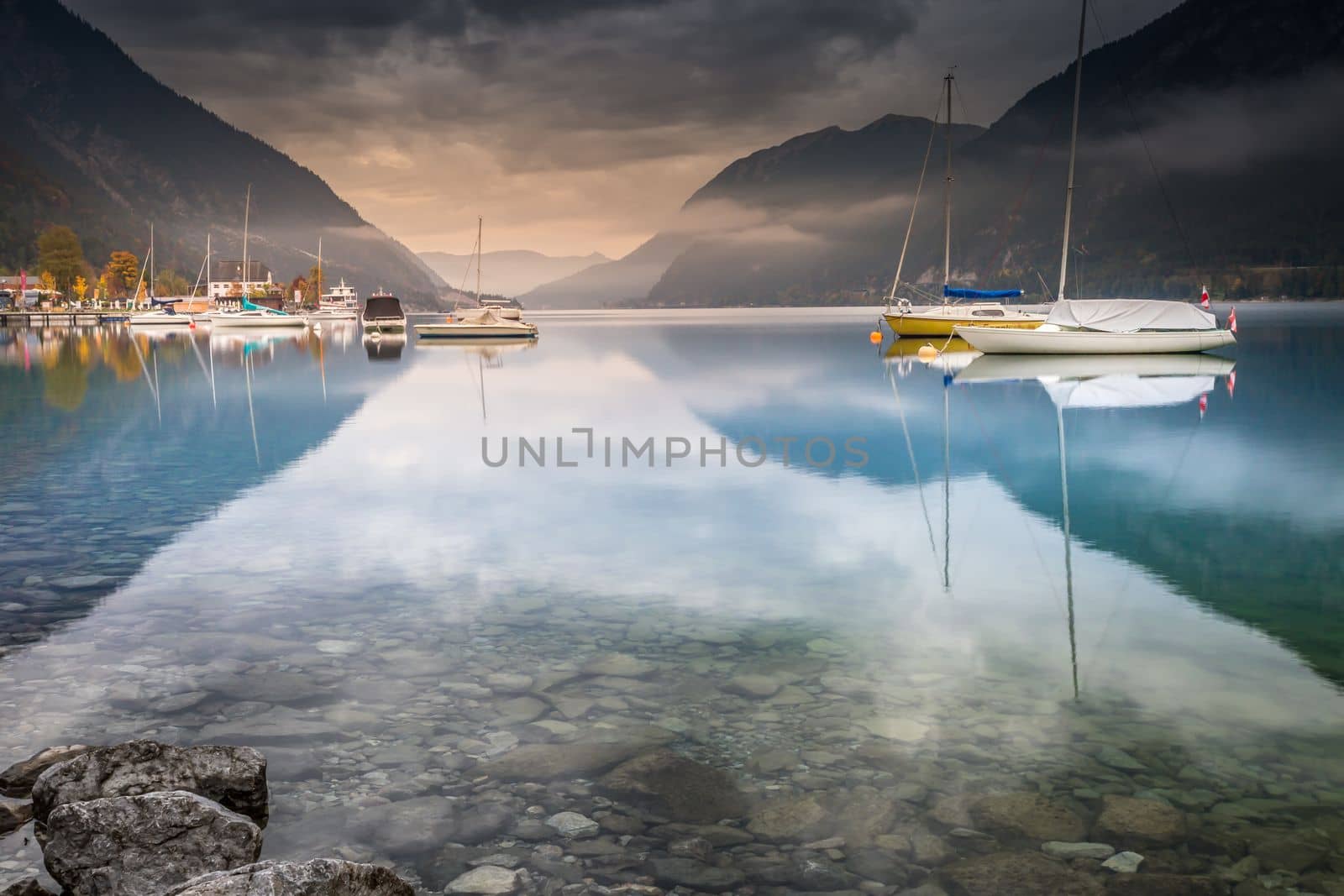 Sailboats on Achensee lake near Innsbruck at peaceful misty dawn, Tyrol alps, Austria