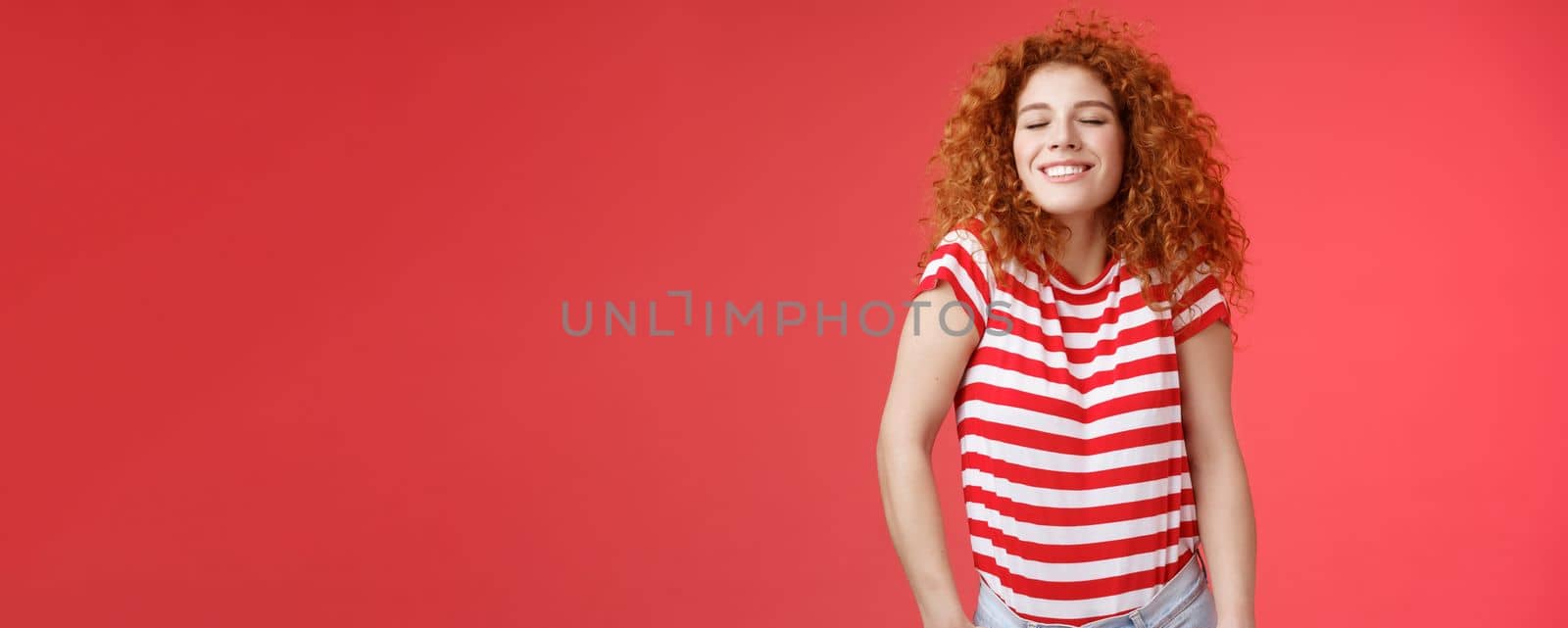Cheerful relaxed carefree happy attractive redhead curly woman close eyes enjoy sunlight warm summer holiday weekends smiling broadly spend vacation sea trip travel joyfully, red background by Benzoix