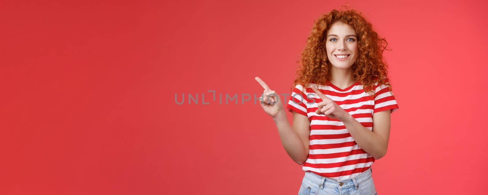 Joyful friendly attractive helpful cute redhead european female advice cool store promo pointing upper left corner blogger showing around perfect place spend summer holidays, red background by Benzoix
