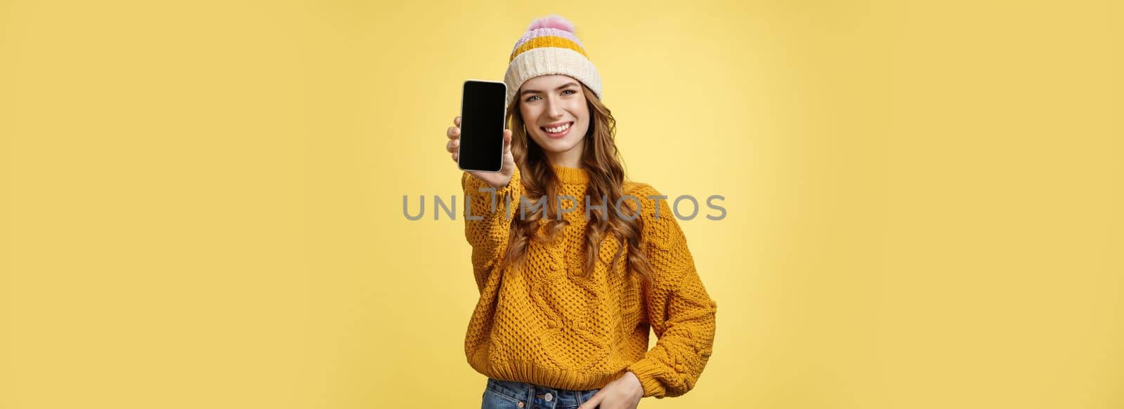 Charming outgoing smiling trendy girl extend arm showing you brand new smartphone, display grinning satisfied consulting friend what filter put using app edit photo mobile phone, yellow background.