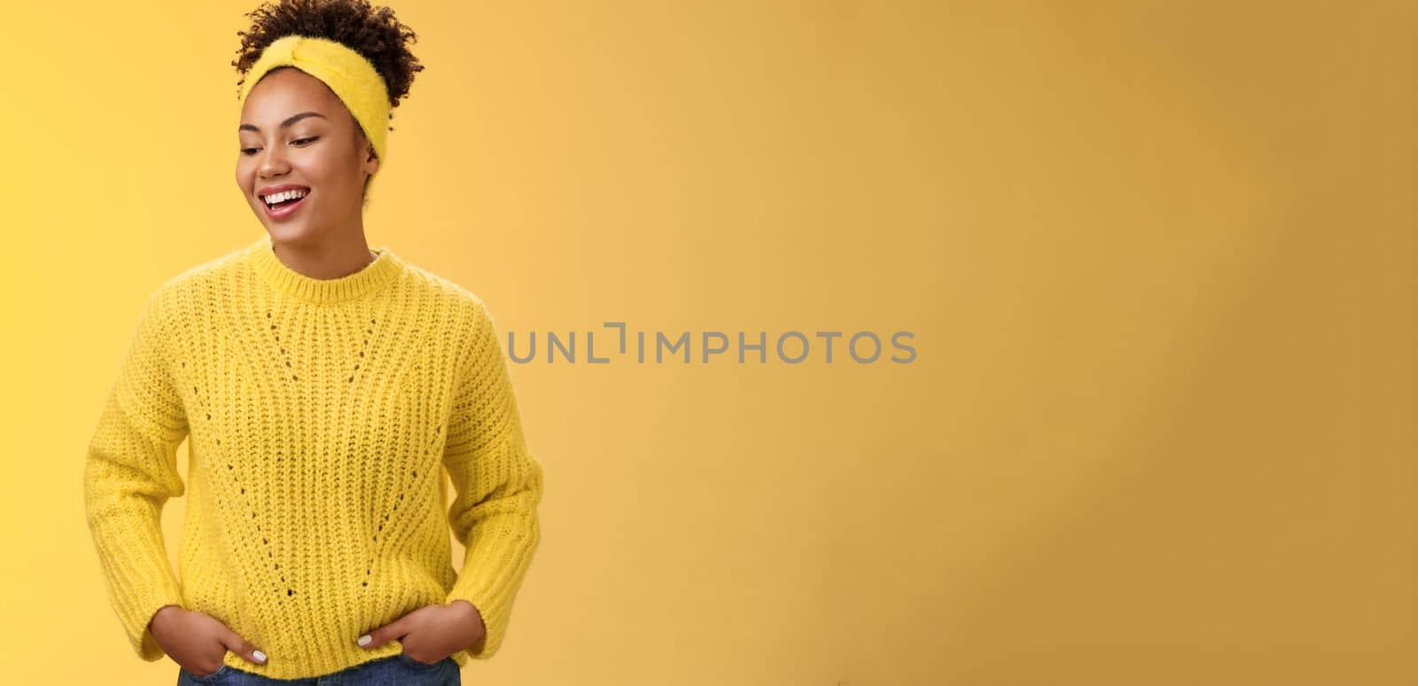 Charismatic carefree lifestyle studio shot african-american woman laughing friendly looking left down hold hands pockets self-assured unbothered relaxed pose, standing chatting yellow background by Benzoix