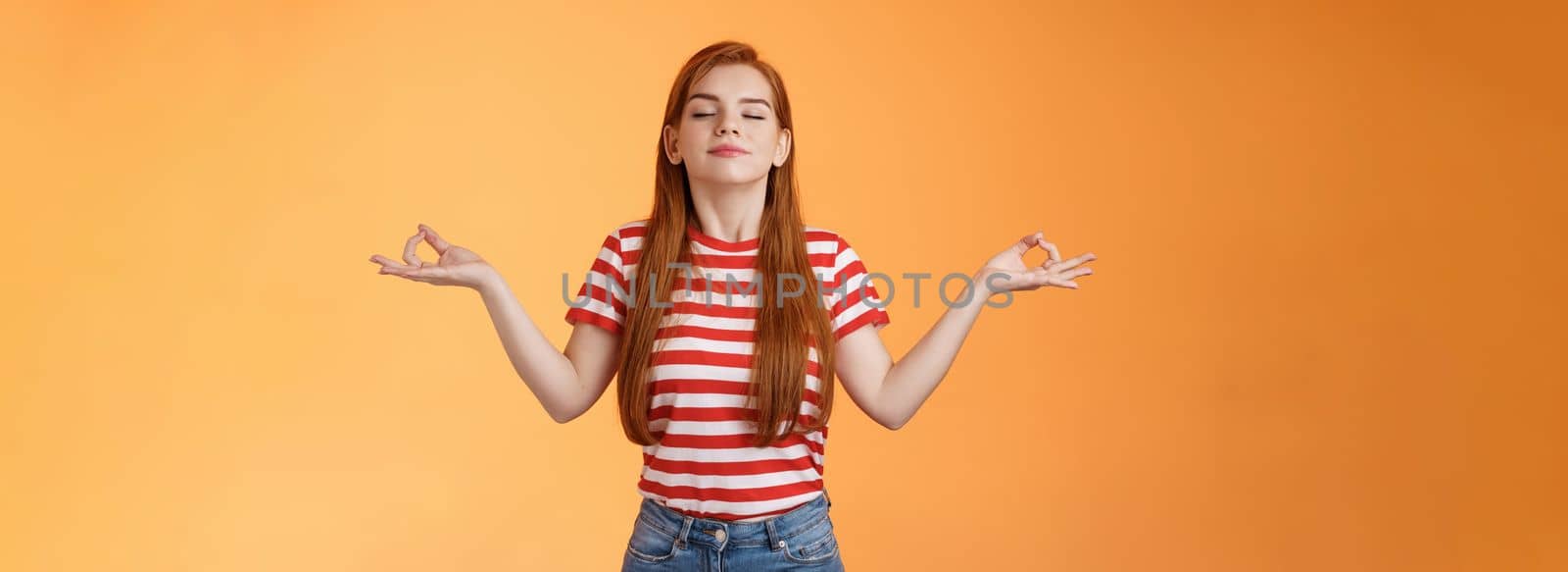 Girl listening relaxing podcast meditating indoors, breath fresh air, close eyes smiling peaceful delighted, stand orange background, chill carefree, enjoy practive yoga, relieve from stress.