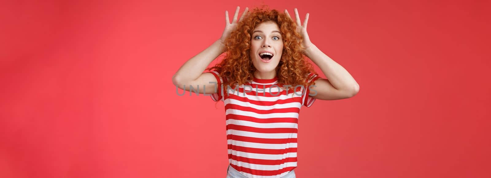 Impressed excited shocked young cute redhead curly-haired ginger girlfriend reacting amazed surprised awesome gift cannot believe own eyes grab head thrilled open mouth ambushed red background by Benzoix