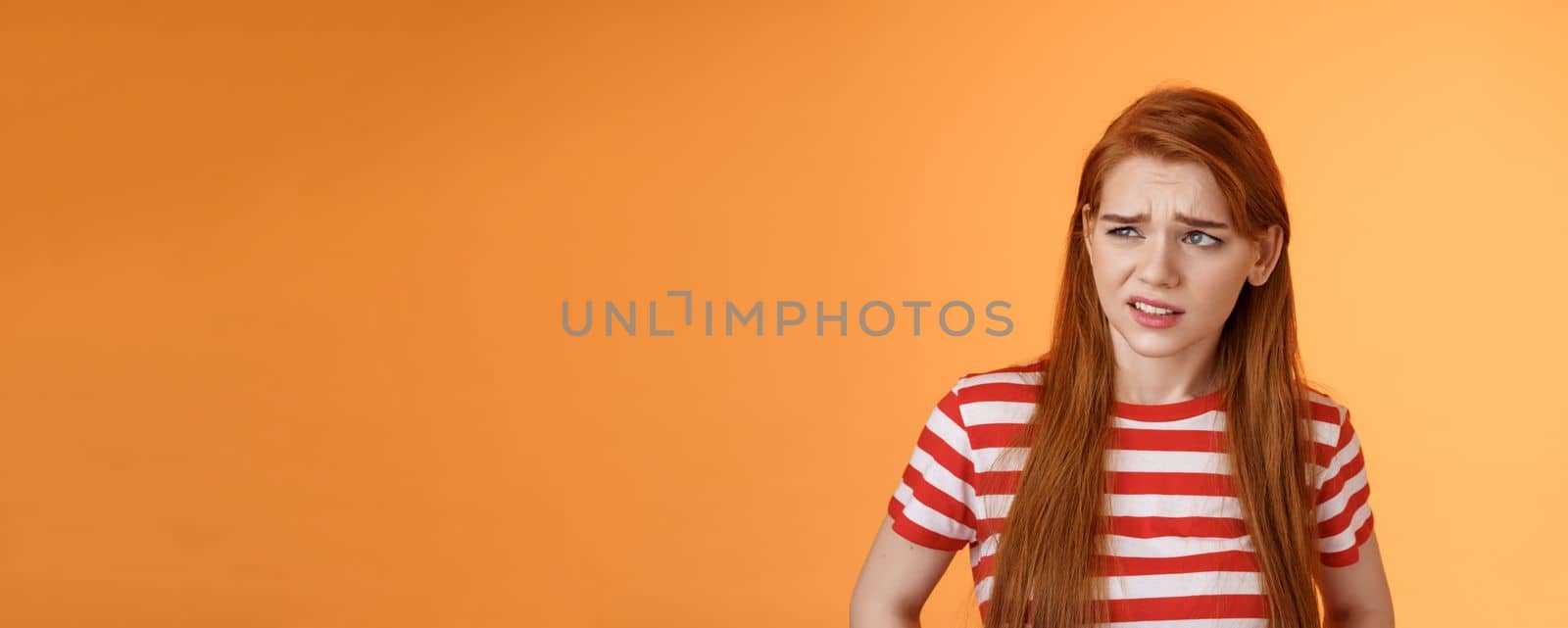 Close-up unsure redhead teenager frowning uncertain, having doubts, look perplexed left side copy space, hesitating, cringe dislike and disappointment, stare frustrated, uneasy decision by Benzoix