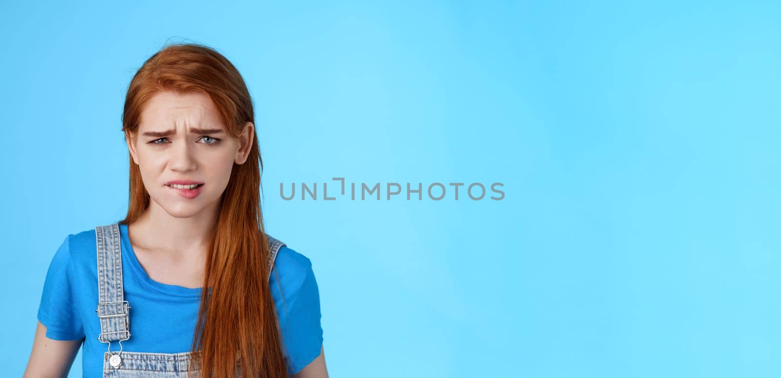 Uneasy upset redhead girl feel uncomfortable, stare frustrated, biting lip frowning, pull sad face upset, apologizing friend, express pity dilsike, stare doubtful uncertain, make bad choice.