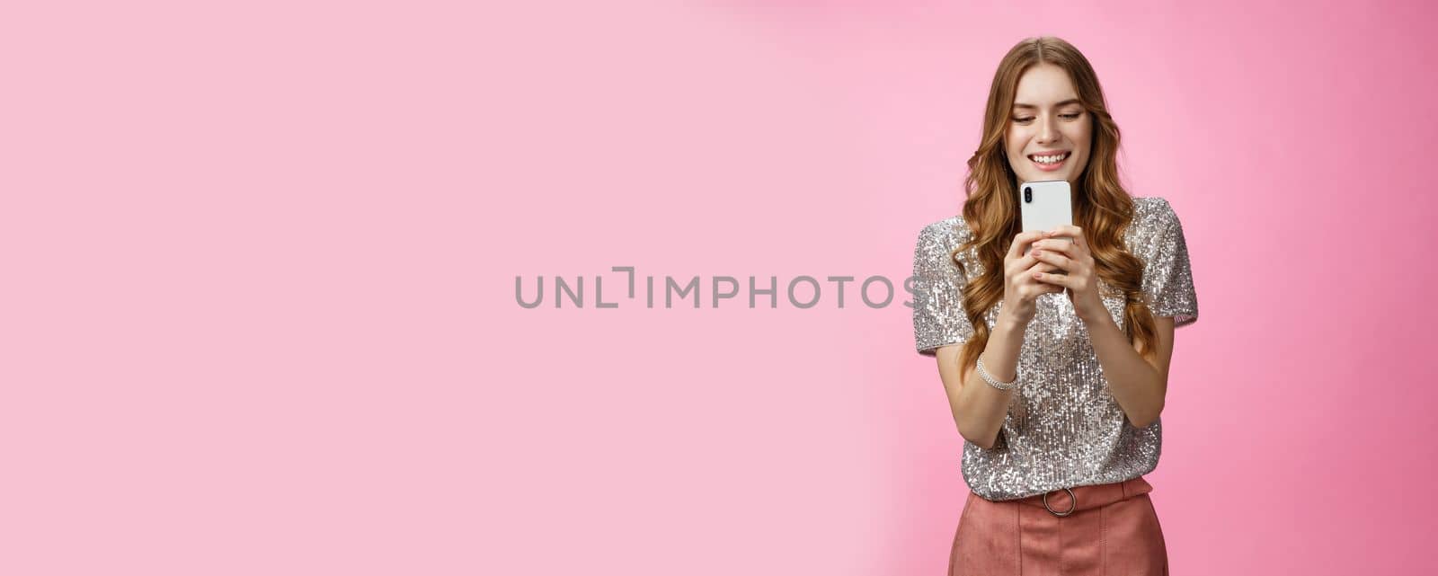 Charming glamour sociable stylish caucasian female using smartphone looking mobile phone screen look gadget display amused writing post upload photo social web page texting, pink background by Benzoix