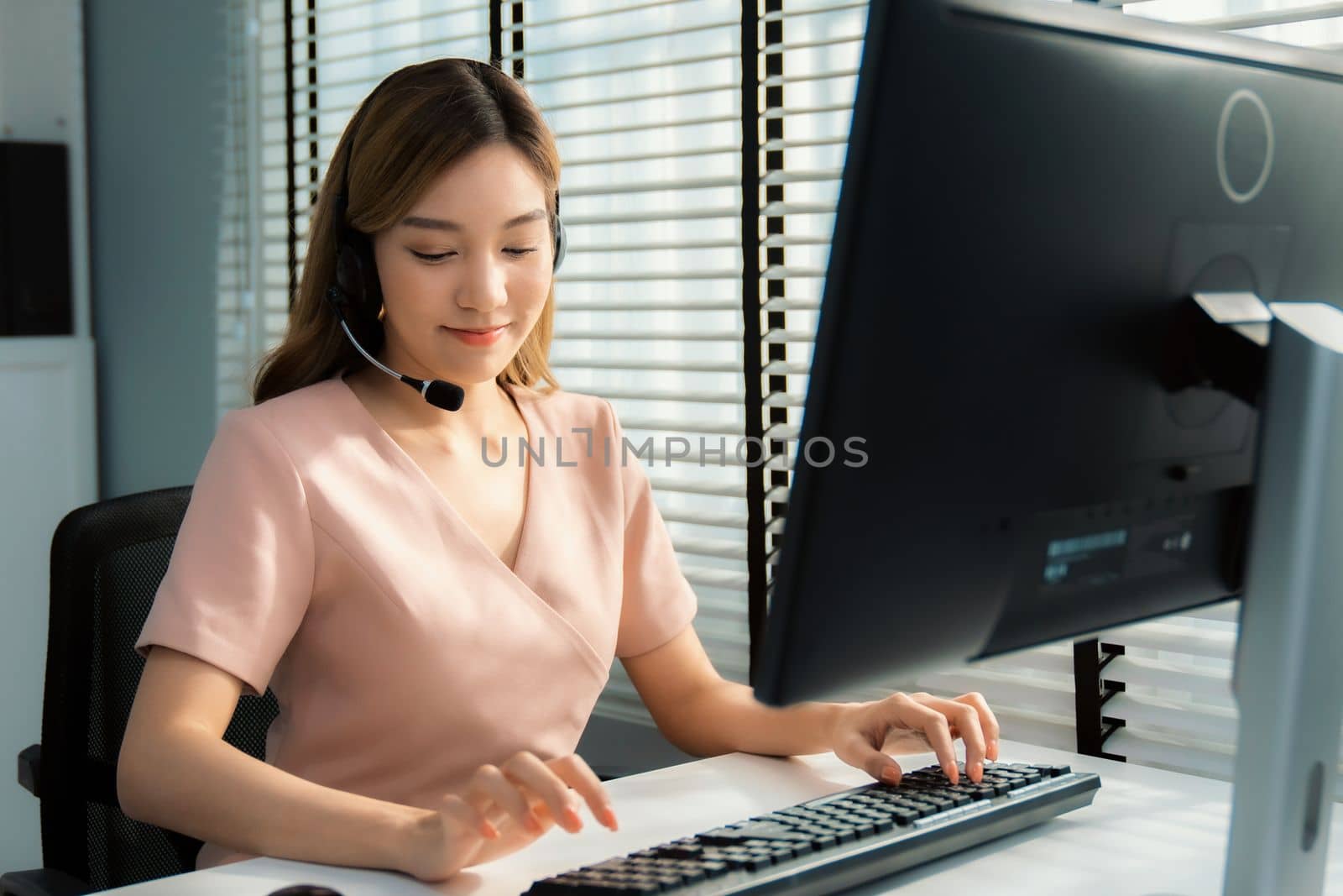 Competent female operator working on computer and while talking with clients. by biancoblue