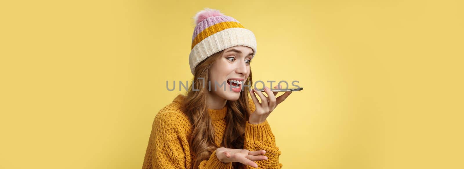 Close-up annoyed angry young woman shouting phone recording audio message irritated arguing having fight friend, raise hand dismay screaming freaked-out, yellow background. Copy space