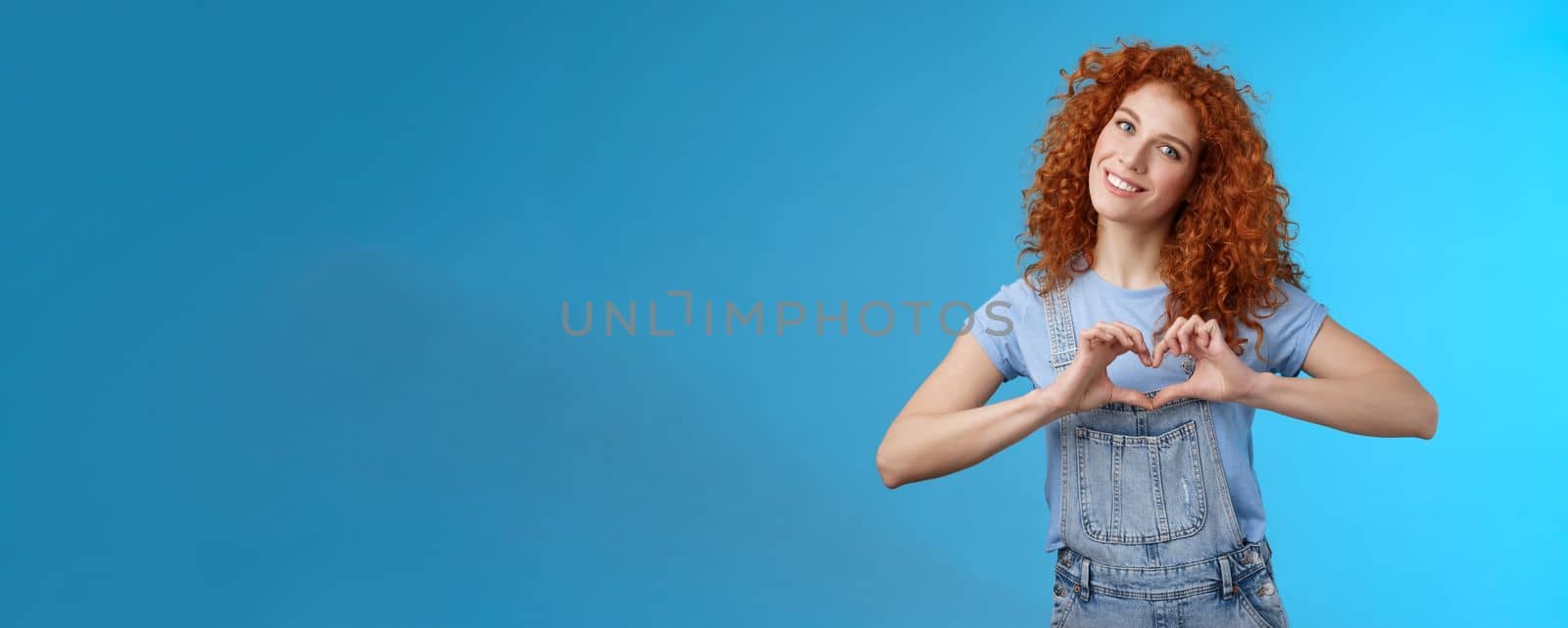 Caring tender lovely redhead girlfriend express sympathy tenderness gentle sympathy tilt head smiling broadly show heart love gesture chest cherish passionate romantic feelings, blue background by Benzoix